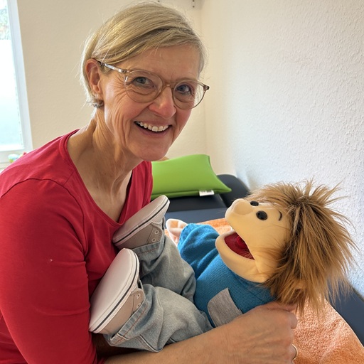 Friederike schaeff hält Handpuppe Sam und lachtin die Kamera.